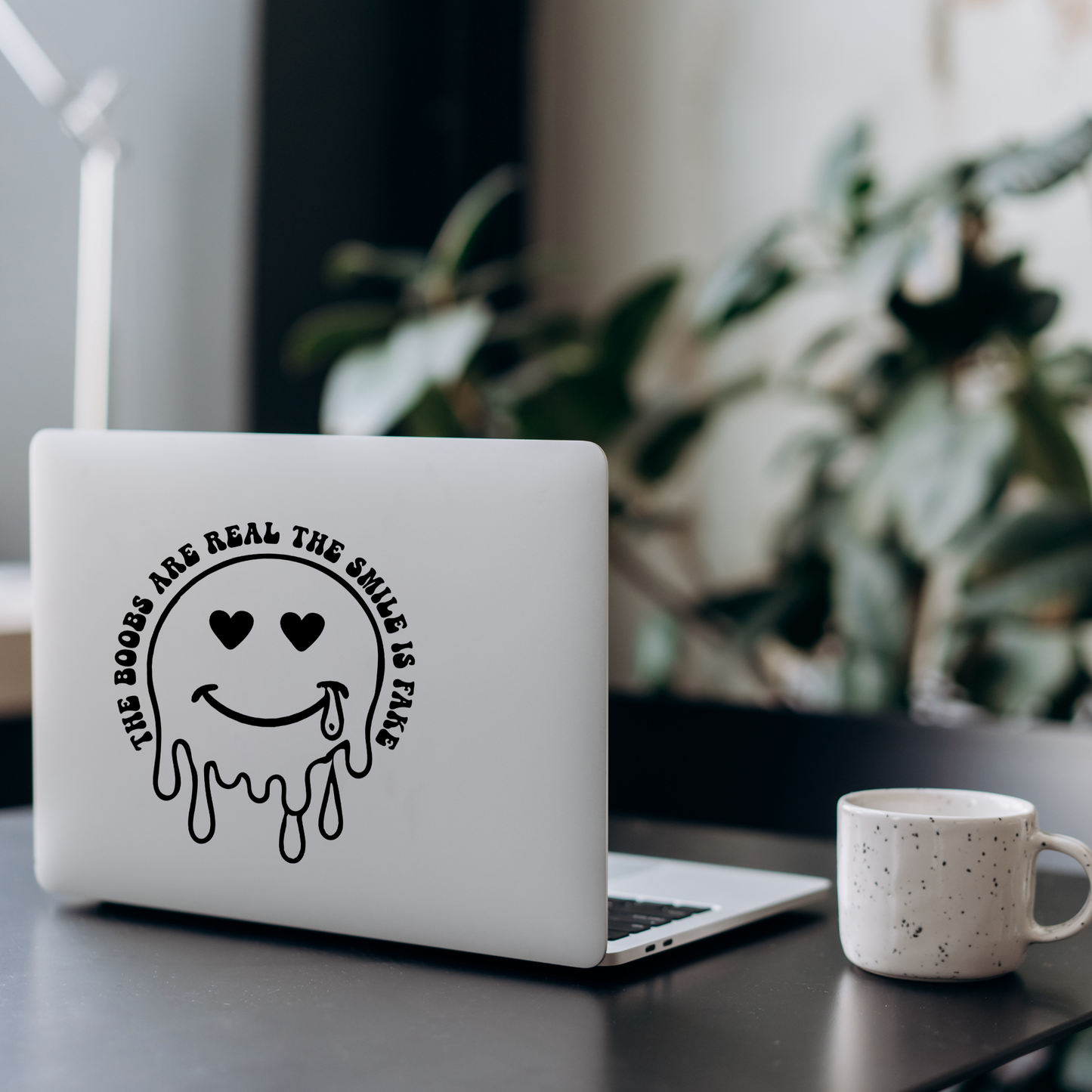 Vinyl decal of a dripping smiley face with heart eyes and a tear, surrounded by text that reads “The Boobs Are Real The Smile Is Fake”