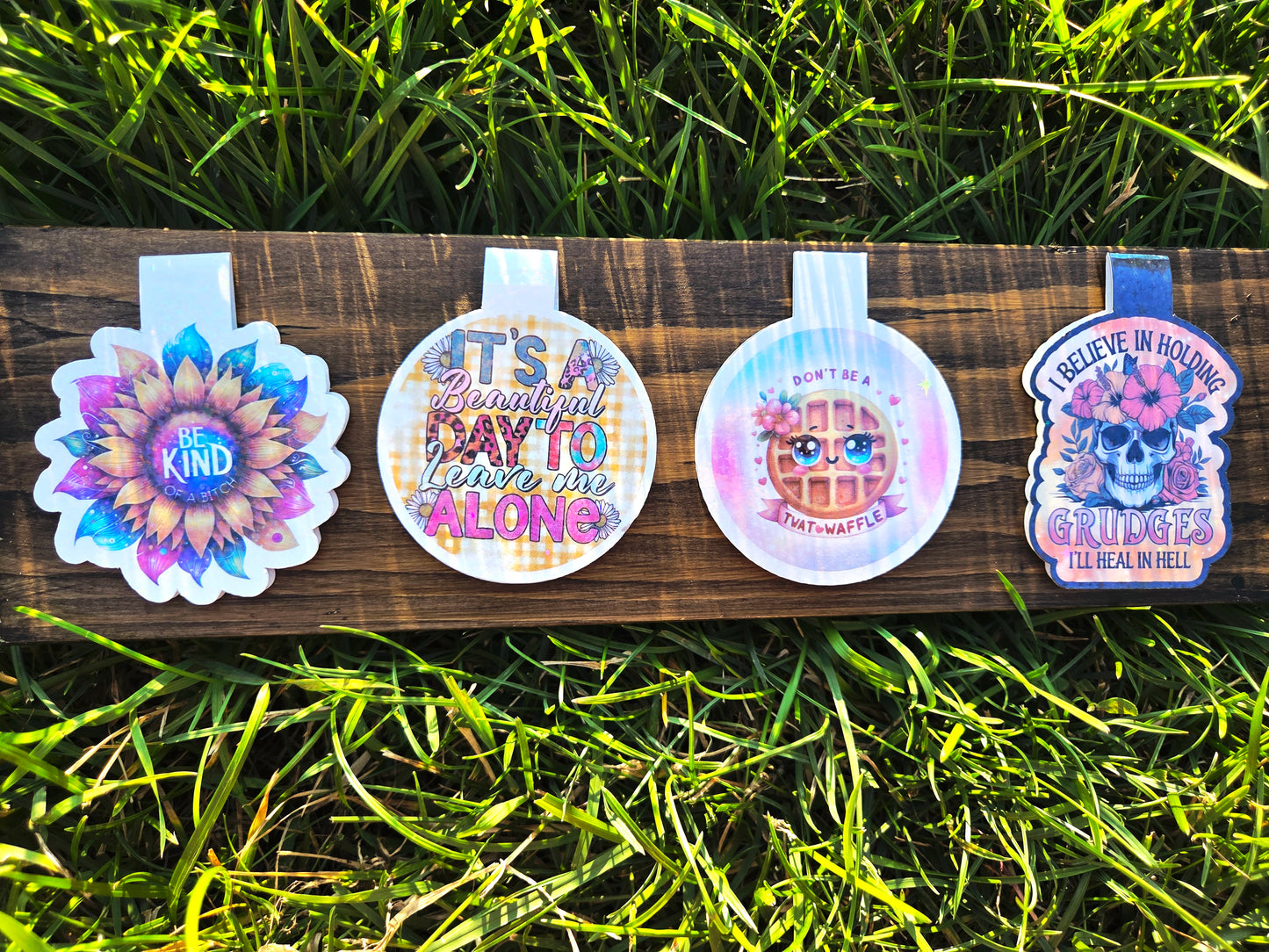 Four colorful bookmarks on a wooden board with grass in the background