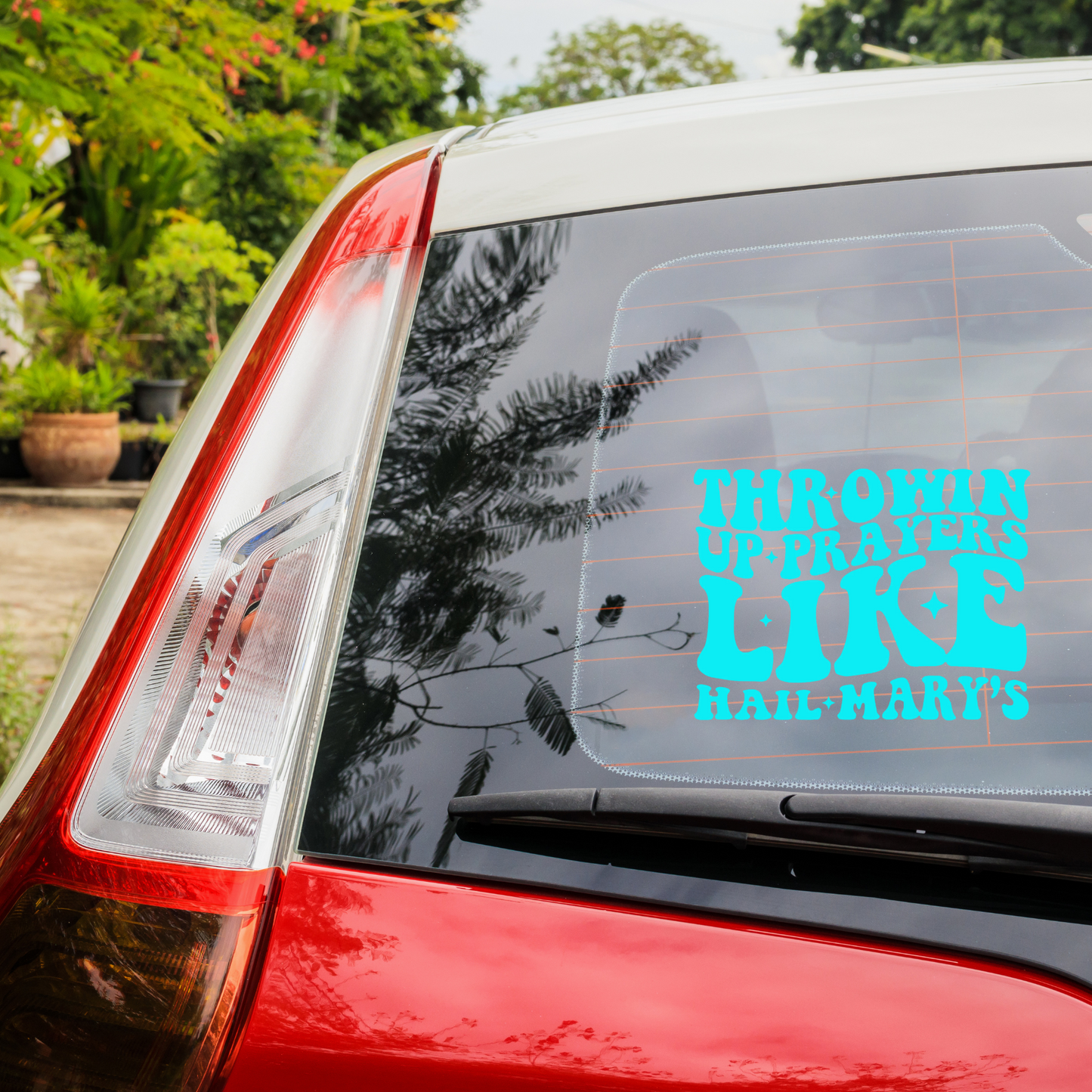 Vinyl decal that says throwin up prayers like hail mary's on the back of a red car