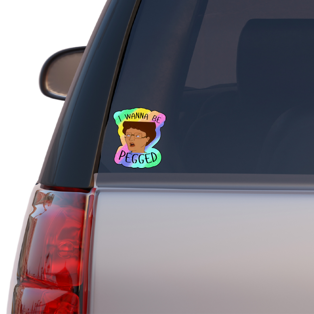 Holographic parody sticker with a cartoon woman and the phrase “I Wanna Be Pegged” in bold black lettering