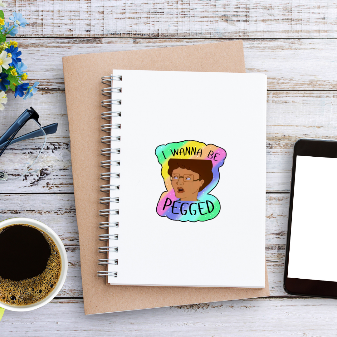 Holographic parody sticker with a cartoon woman and the phrase “I Wanna Be Pegged” in bold black lettering