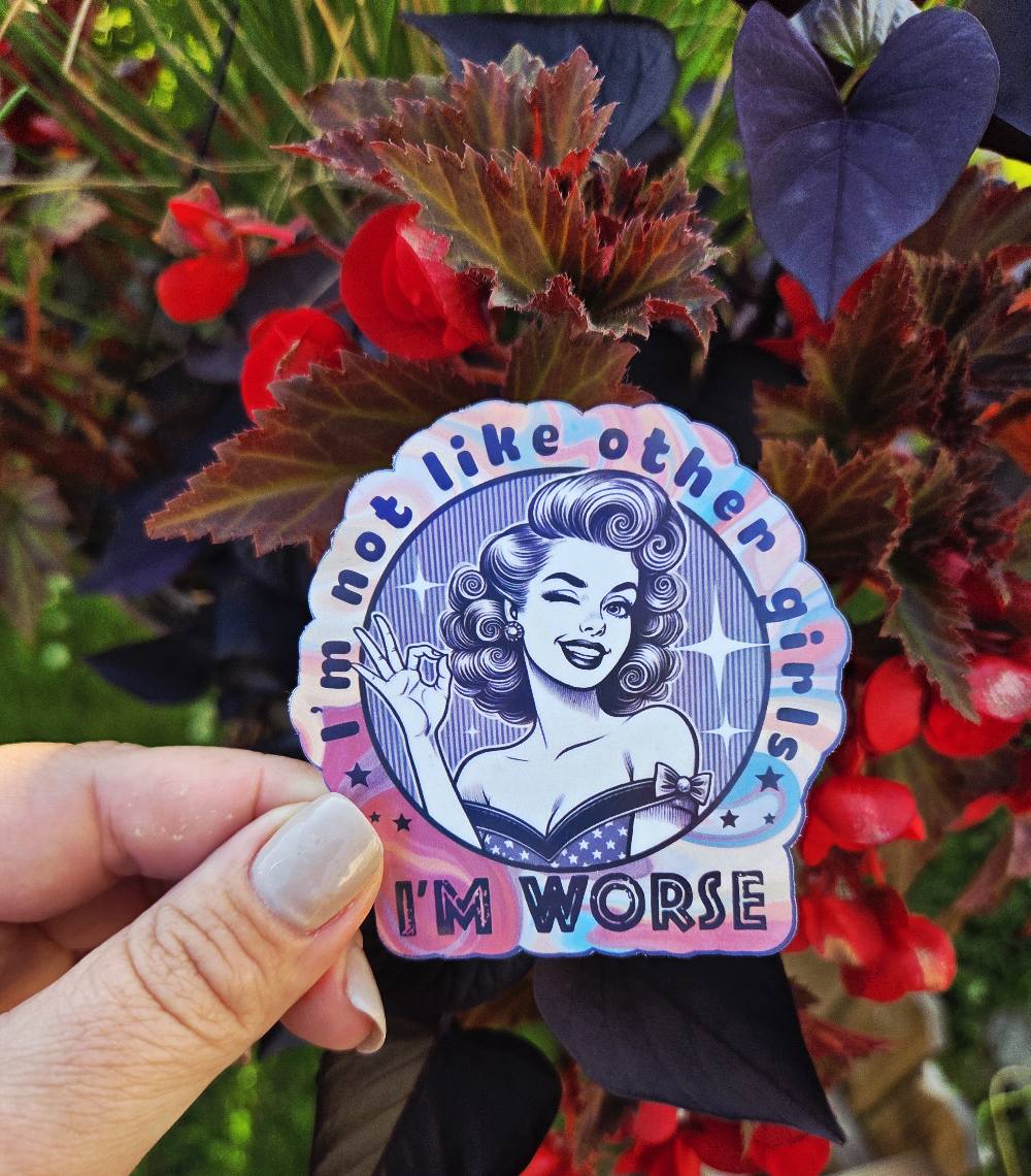 Sticker featuring a retro pin-up girl with curled hair, winking and giving an OK hand gesture, surrounded by the phrase “I’m not like other girls – I’m worse” on a colorful background