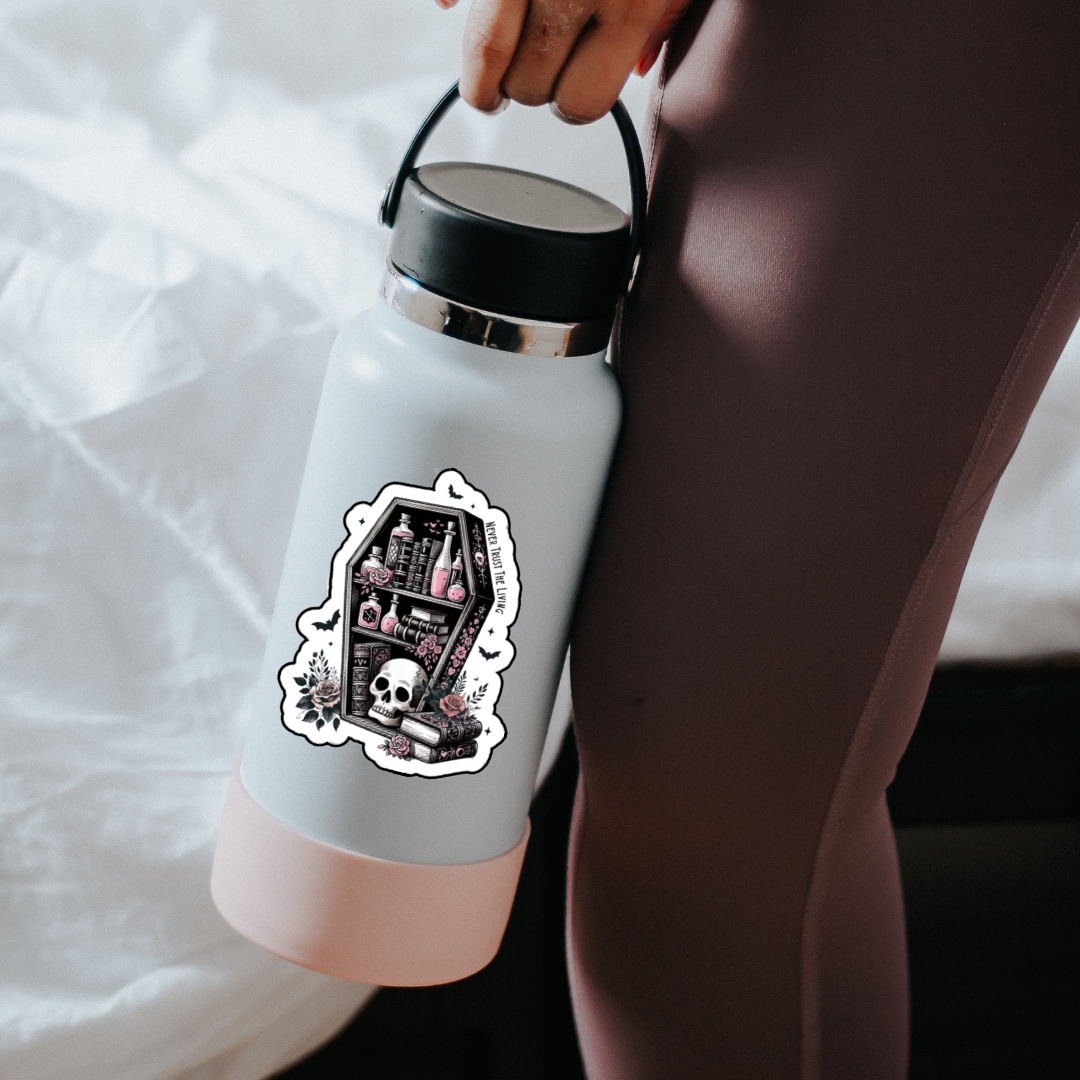 Sticker shaped like a coffin bookshelf with books, pink potion bottles, roses, and a skull, surrounded by bats and flowers. Text along the side reads “Never Trust the Living.”