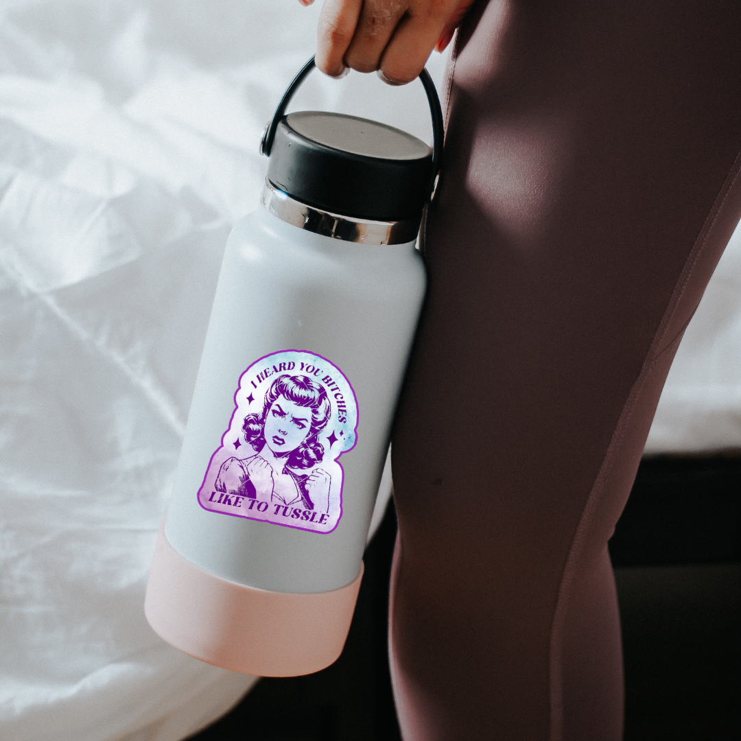 Sticker featuring a vintage-style woman with fists up and the phrase “I Heard You Bitches Like to Tussle” in purple and teal tones