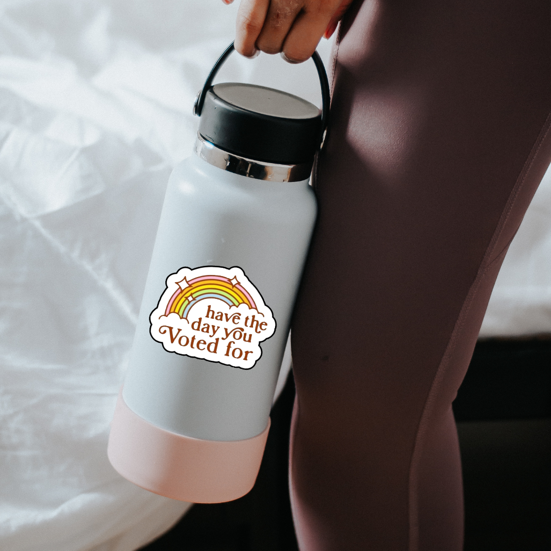 Retro rainbow sticker with the phrase “Have the Day You Voted For” in bold brown text and sparkles