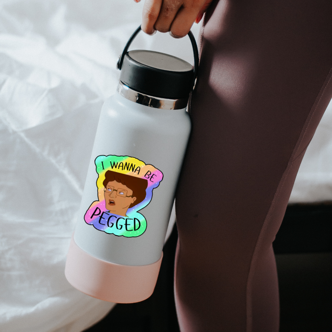 Holographic parody sticker with a cartoon woman and the phrase “I Wanna Be Pegged” in bold black lettering