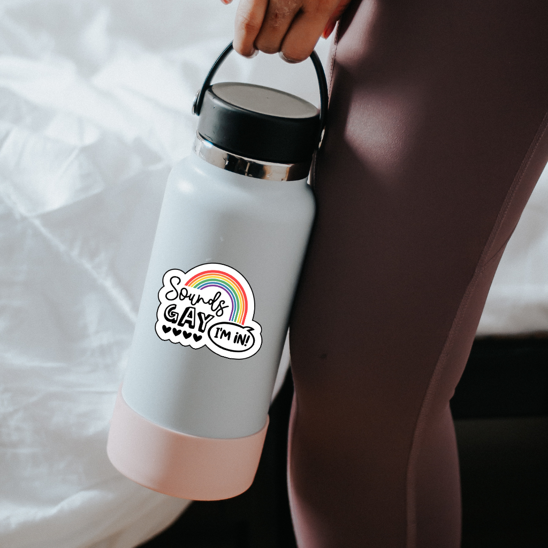 Vinyl sticker with rainbow arch and the phrase “Sounds Gay, I’m In!” in playful black font with five hearts beneath the word "Gay"