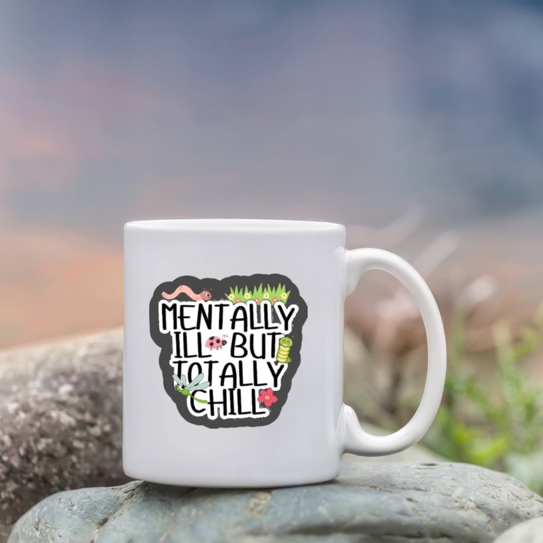 Holographic sticker that says “Mentally Ill But Totally Chill” with bugs, grass, and sparkles