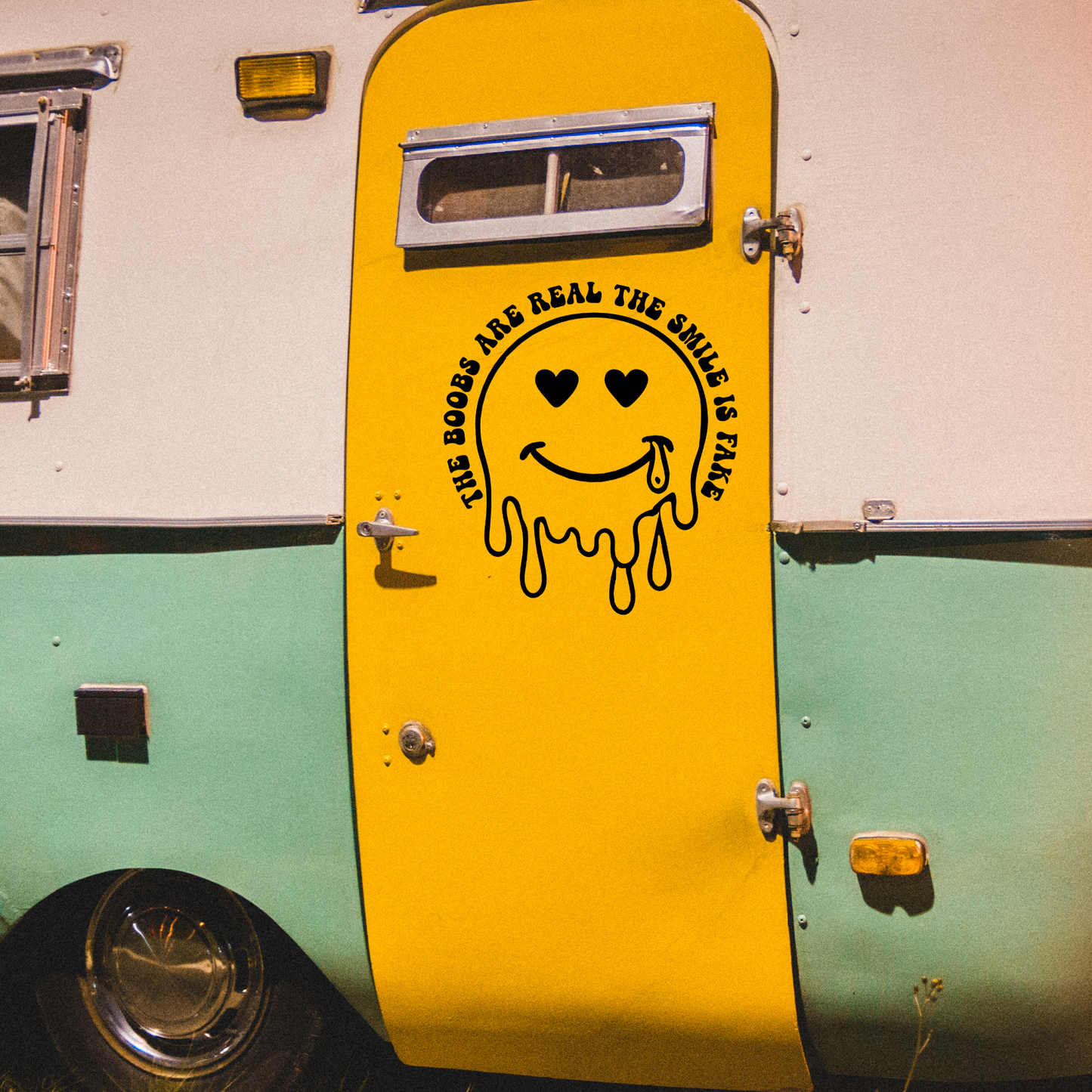 Vinyl decal of a dripping smiley face with heart eyes and a tear, surrounded by text that reads “The Boobs Are Real The Smile Is Fake”