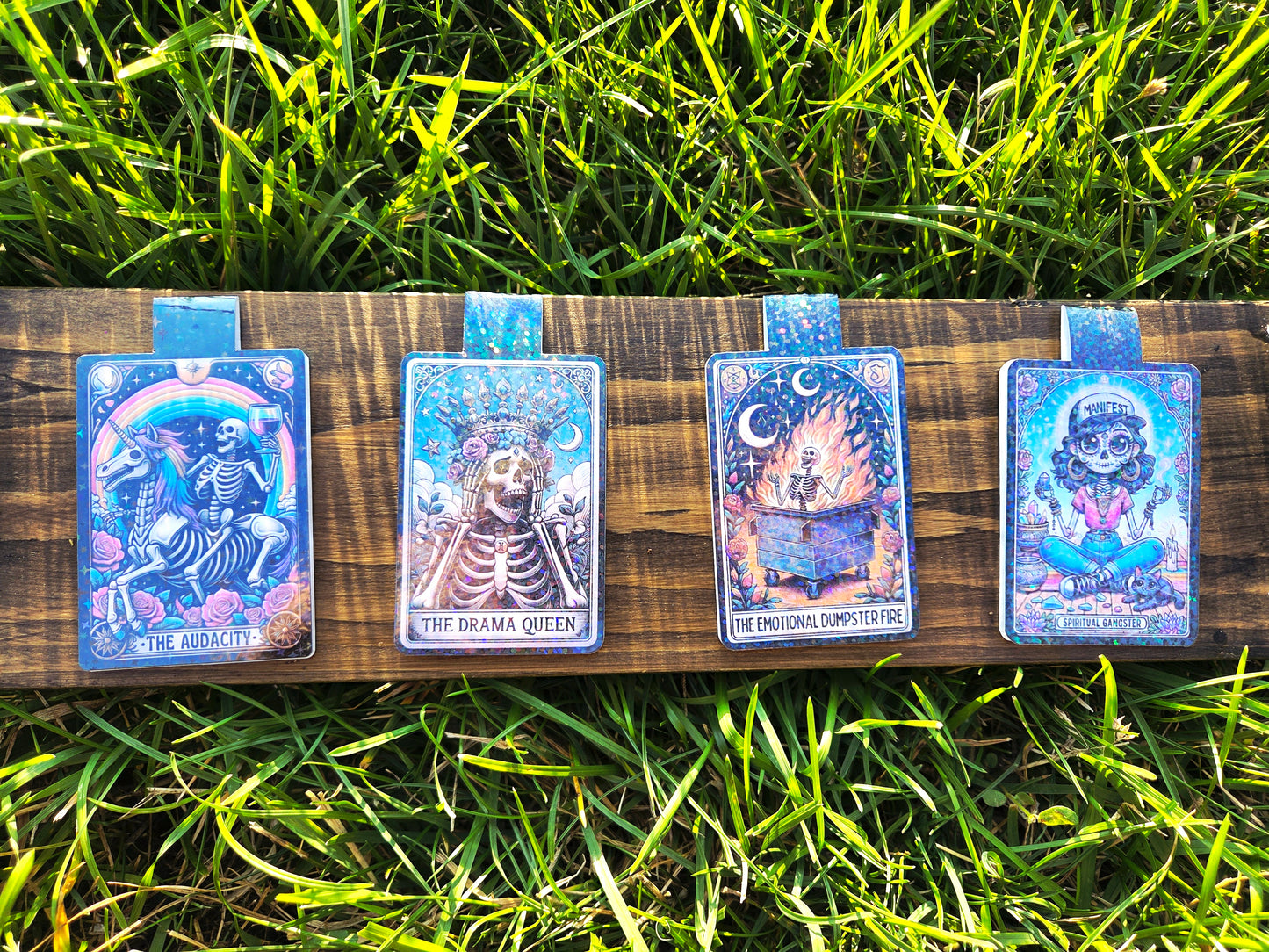 Four tarot card magnets on a wooden board with grass in the background
