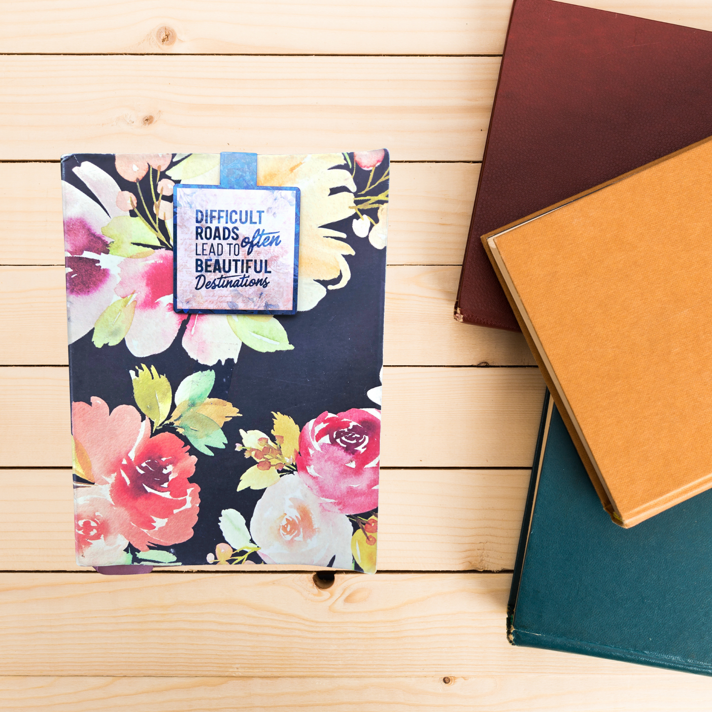 Floral notebook with motivational quote bookmark on a wooden surface