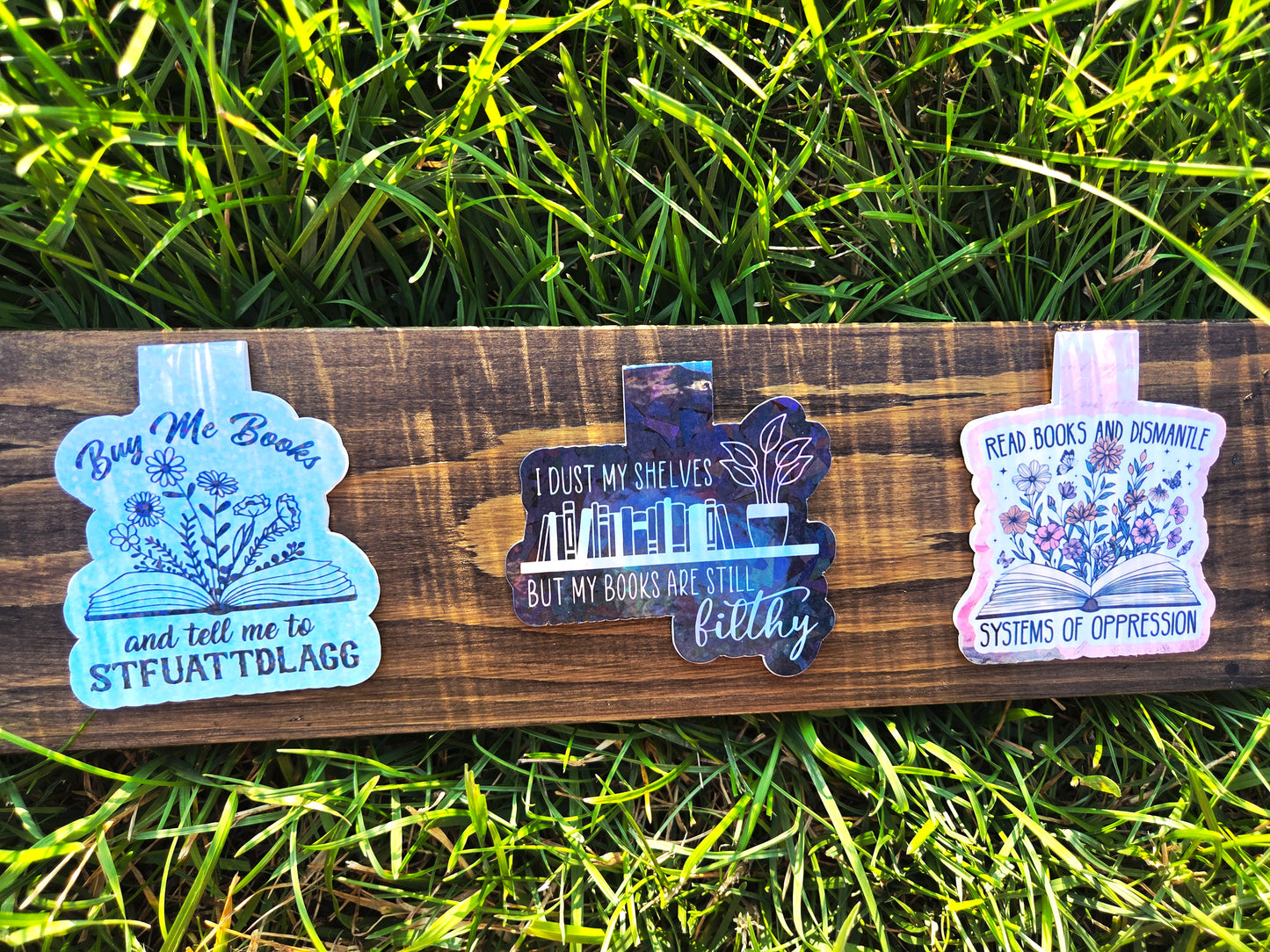 Three colorful bookmarks on a wooden board with grass in the background