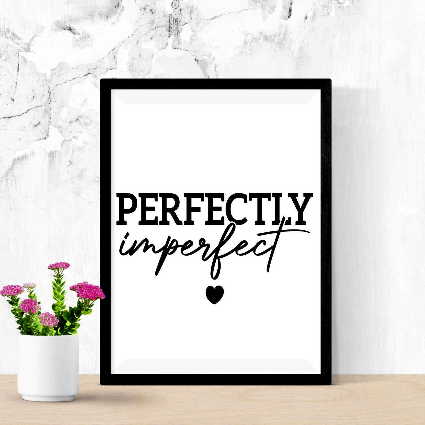 Framed artwork with a silhouette and text on a white wall with a plant below.