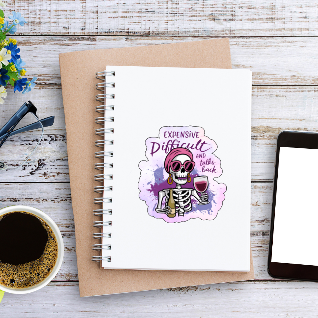 Notebook with a skull illustration on a wooden surface with a cup of coffee and tablet.