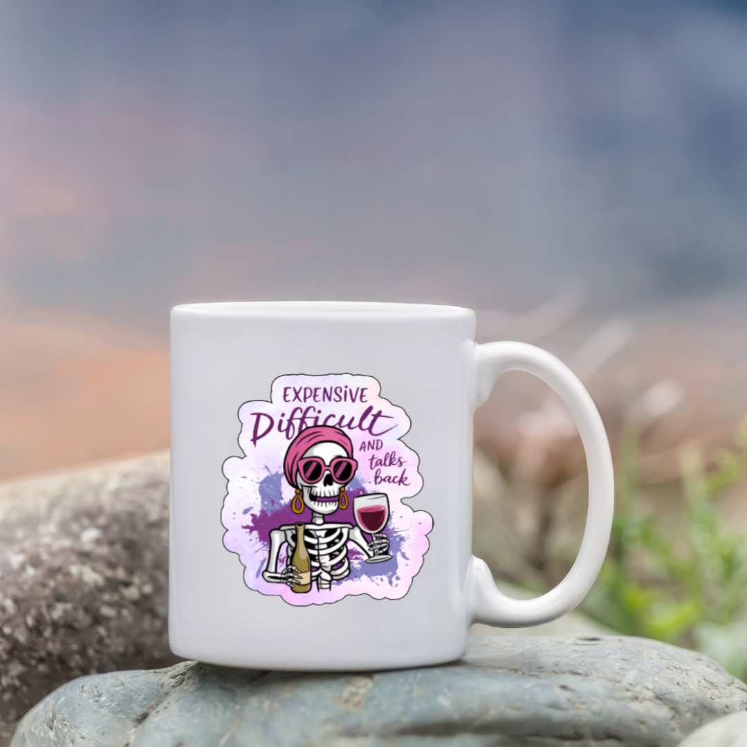 White mug with a floral design and text on a rock with a blurred natural background