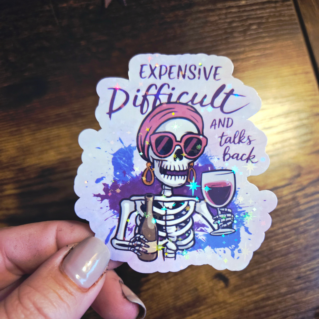 Sticker with a skeleton holding a glass of wine and text on a wooden surface