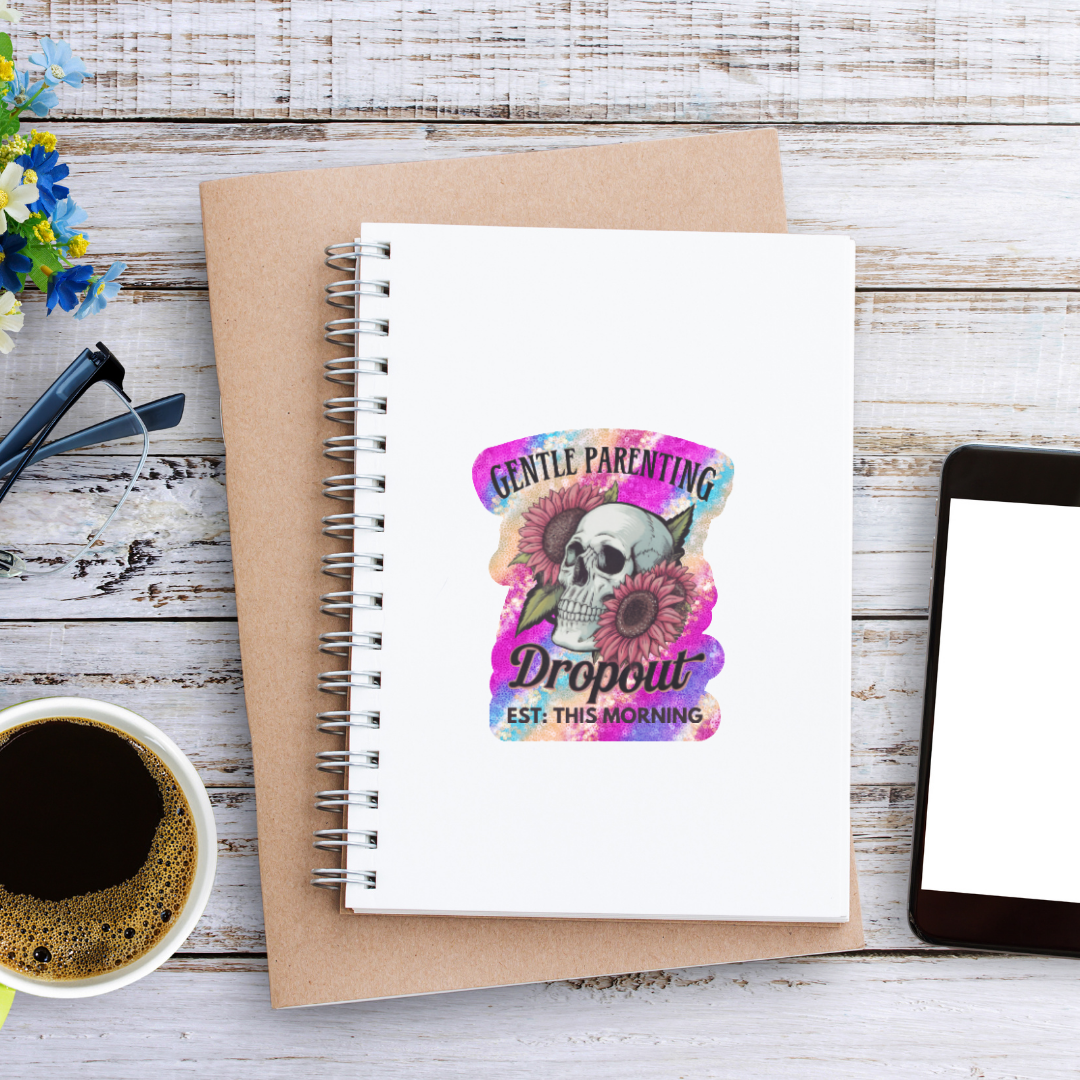 Notebook with a colorful skull design on a wooden surface with a cup of coffee and tablet.