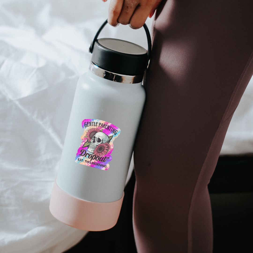 White and pink insulated bottle with a colorful label held by a person.