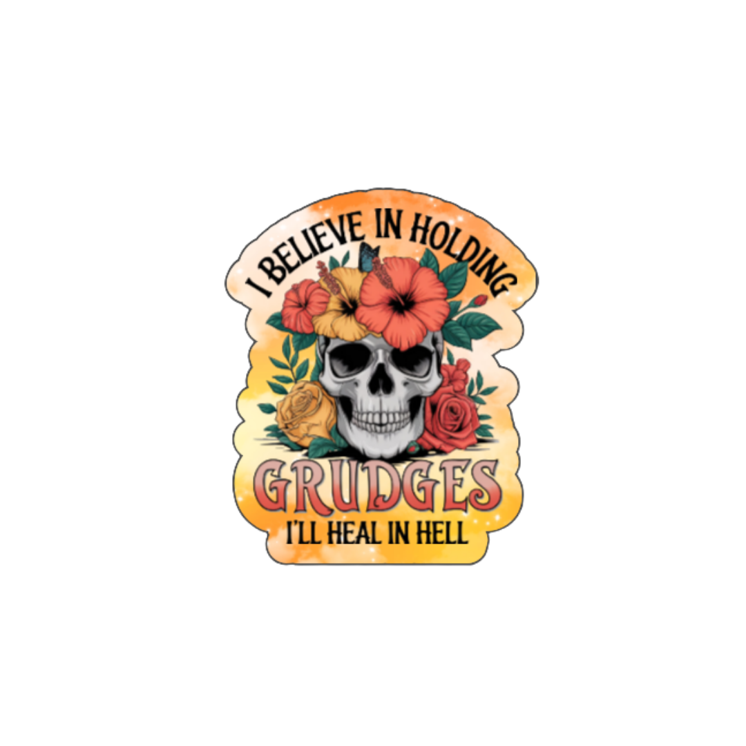 Holographic sticker with a floral-decorated skull and bright orange accents. Text reads “I Believe in Holding Grudges – I’ll Heal in Hell.”