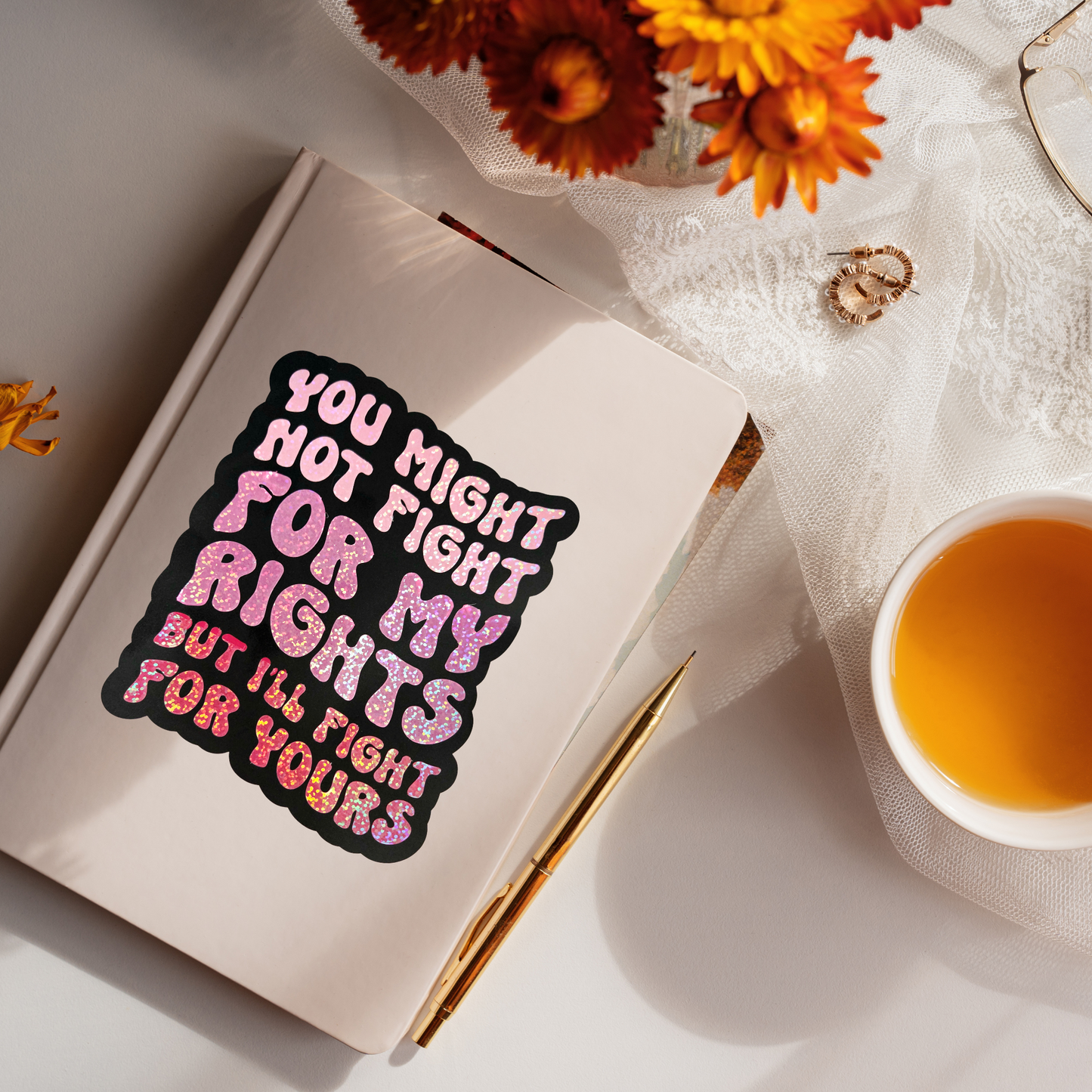 Notebook with a motivational quote, cup of tea, and flowers on a light surface