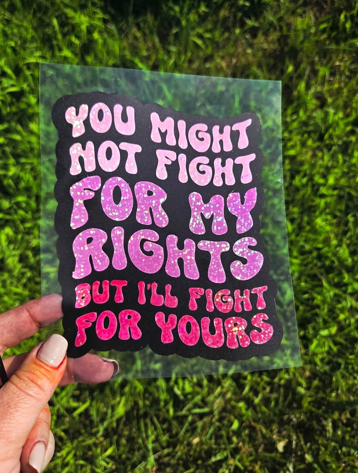 Sticker with text 'You might not fight for my rights but I'll fight for yours' held over grass.