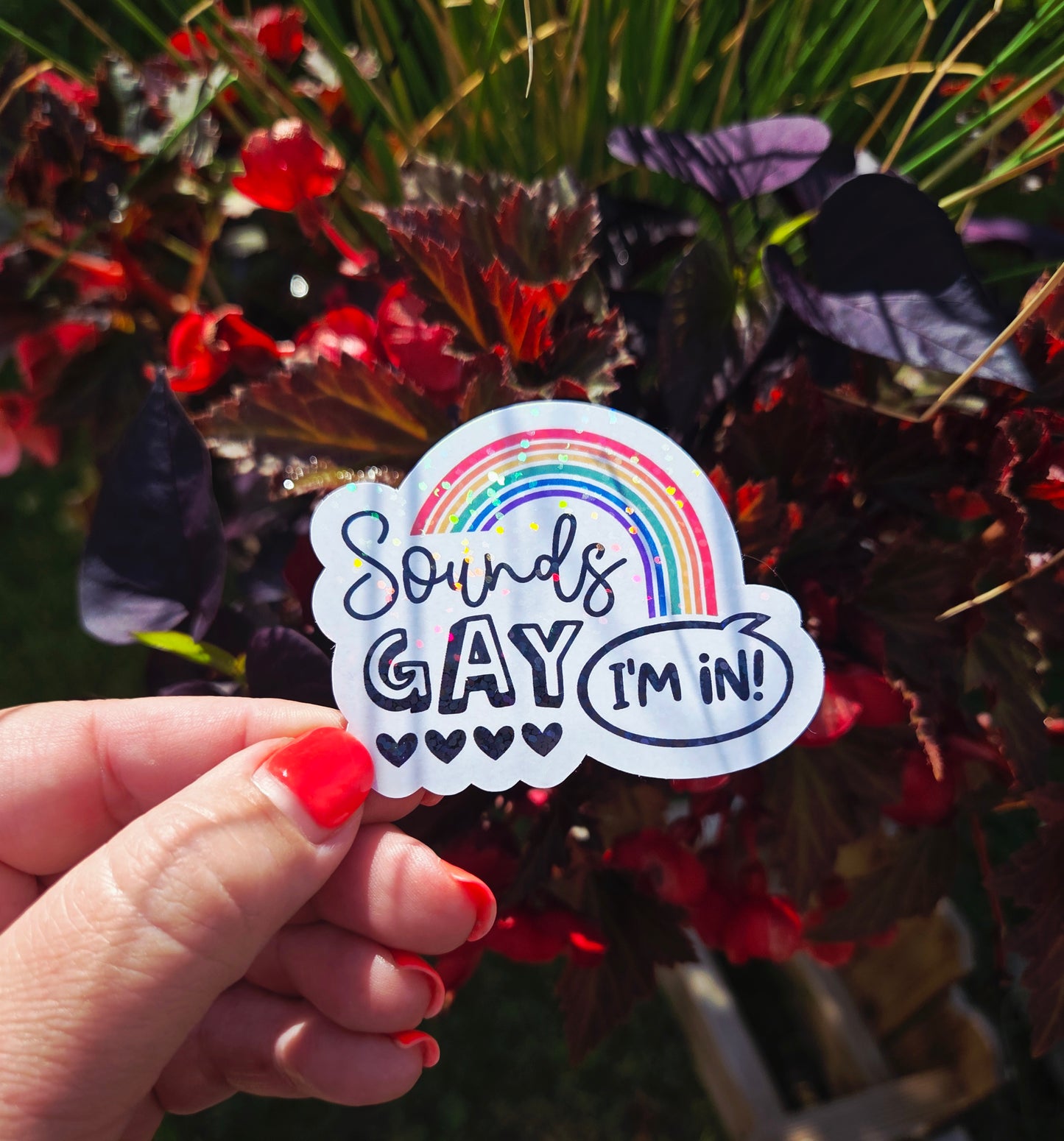 Vinyl sticker with rainbow arch and the phrase “Sounds Gay, I’m In!” in playful black font with five hearts beneath the word "Gay"