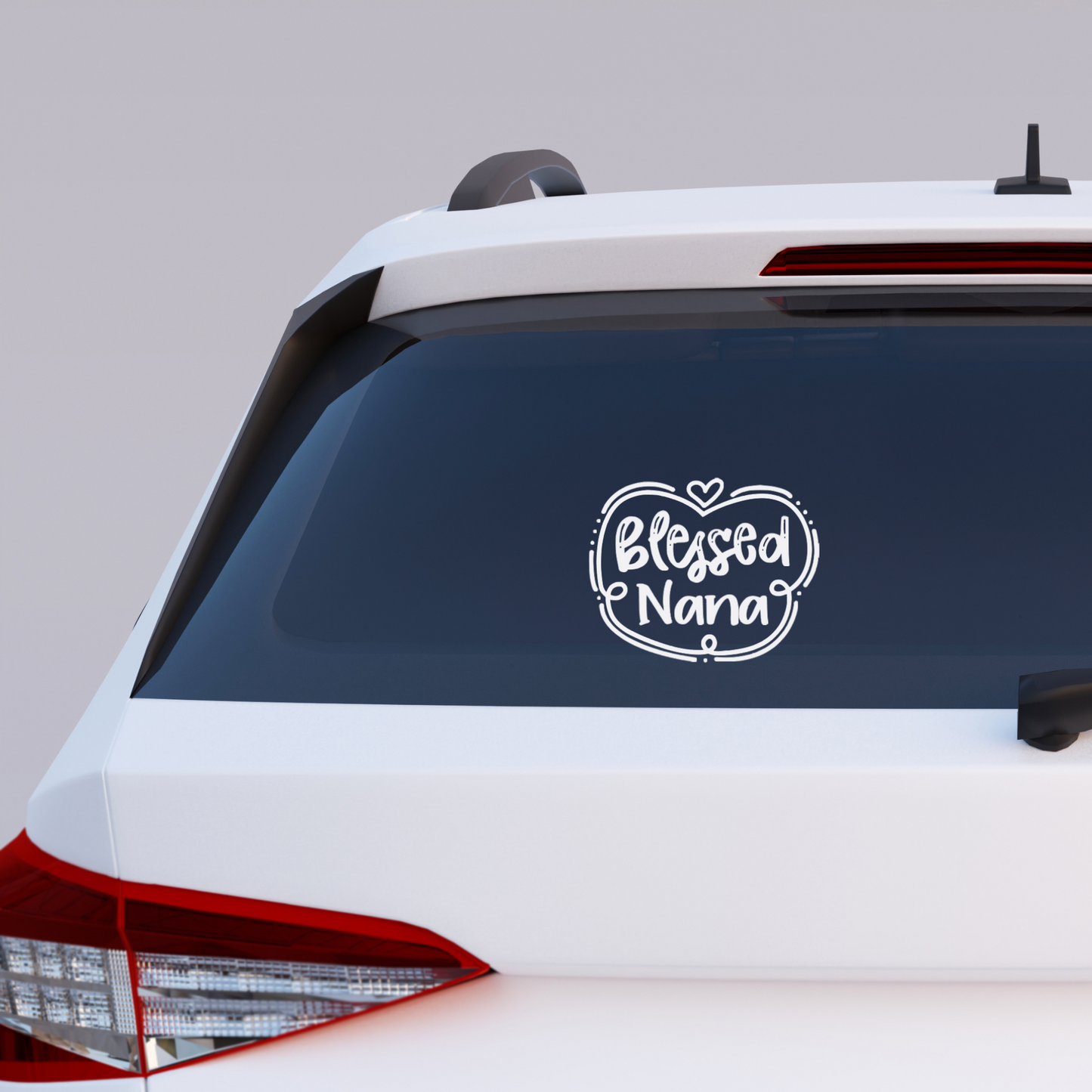 Black vinyl decal that reads “Blessed Nana” in playful hand lettering with heart and swirly border design