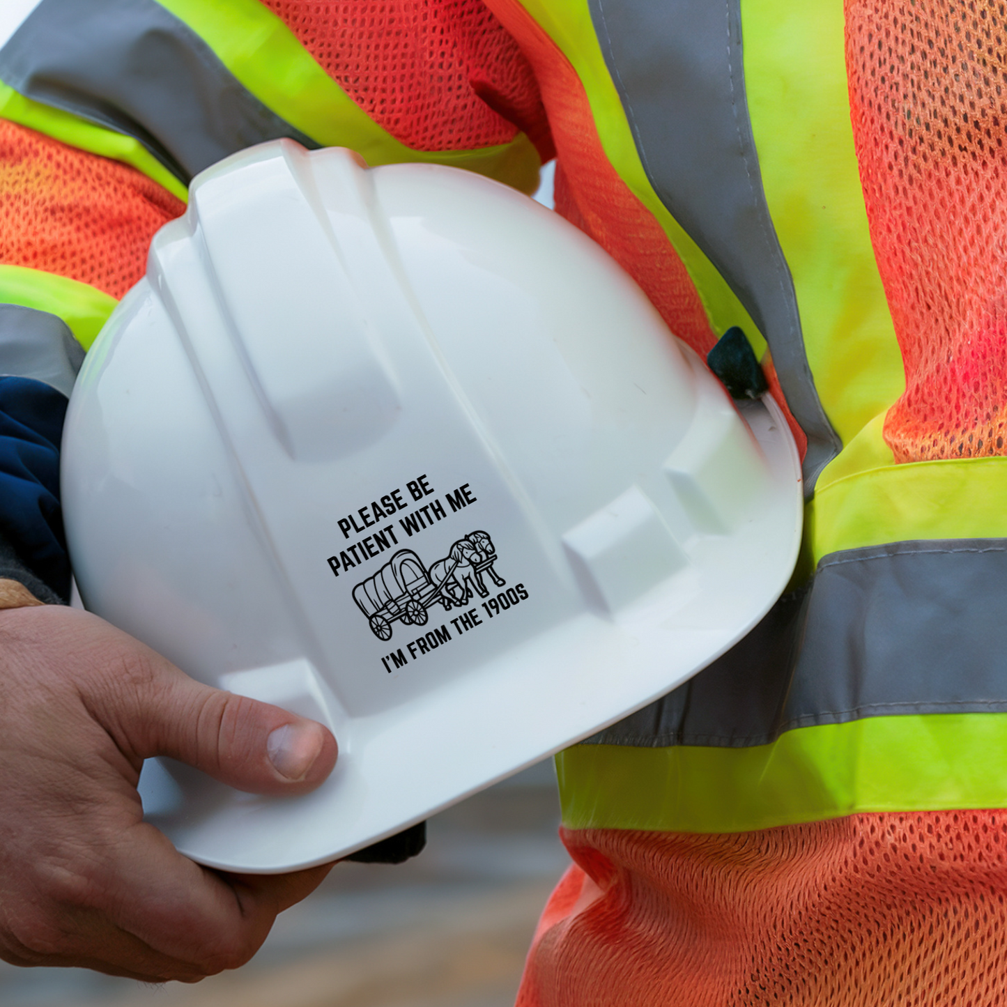 Black and white funny vinyl sticker with a covered wagon and two horses. Text reads: "Please be patient with me – I'm from the 1900s." Ideal for millennial humor lovers.
On a hard hat being held by a person in an orange and yellow high visibility vest.