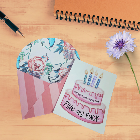 Greeting card with birthday cake illustration and envelope on a wooden surface