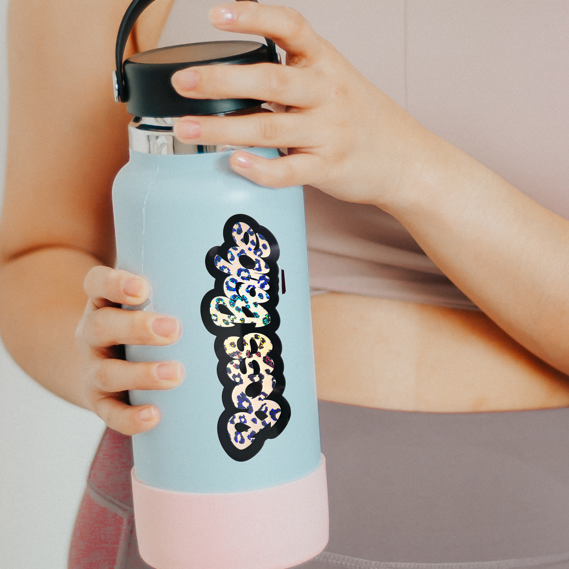 Light blue water bottle with a decorative patch held by a person