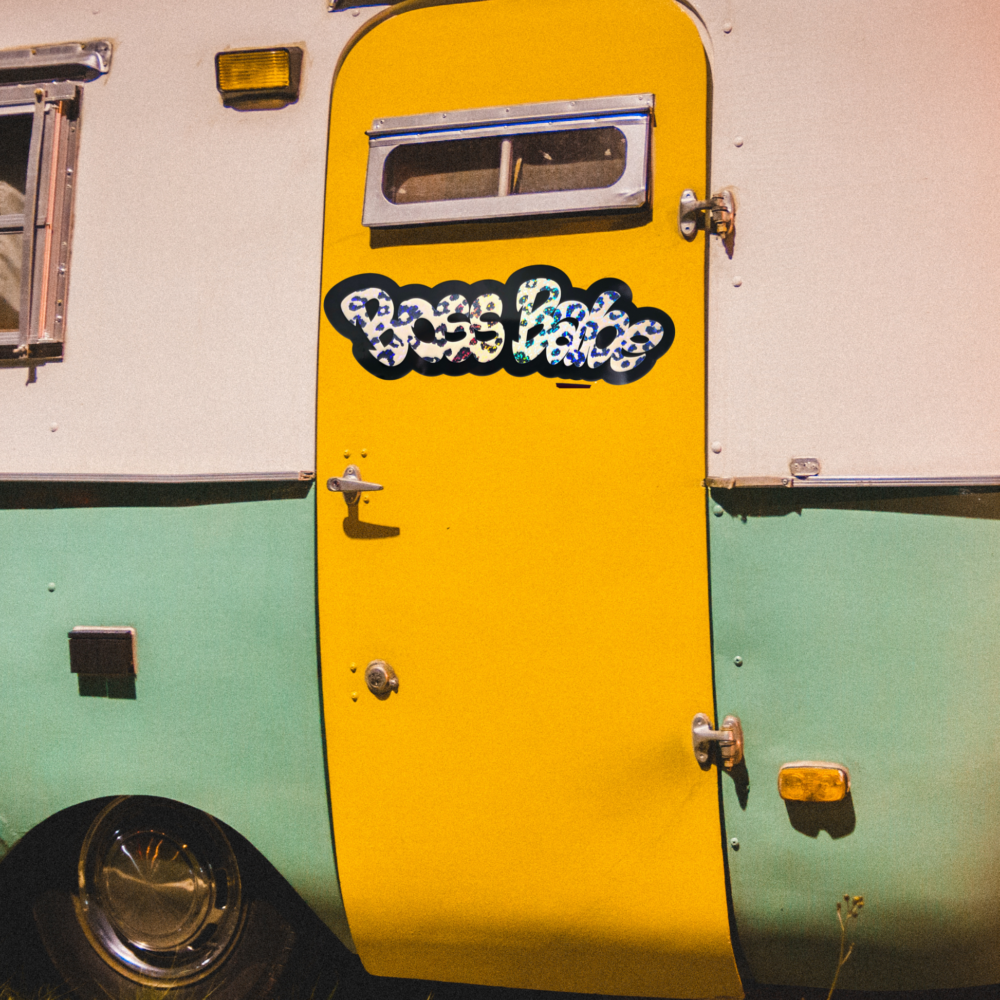 Yellow door of a vintage-style trailer with Boss Babe decal.