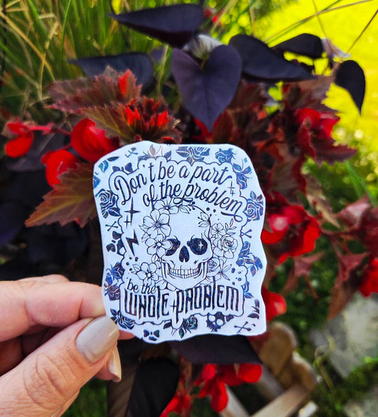 Black and white sticker of a skull surrounded by flowers with the phrase “Don’t be a part of the problem, be the whole problem”