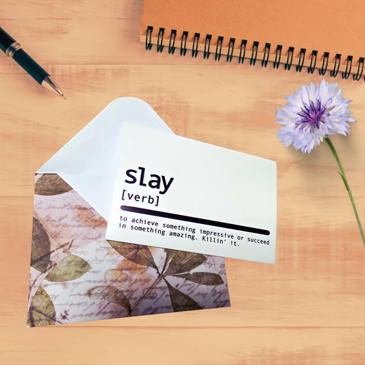 Notebook with a floral design, a pen, and a flower on a wooden surface