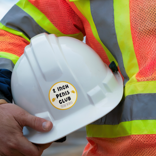 Person wearing a high-visibility safety vest holding a white hard hat with a sticker.
