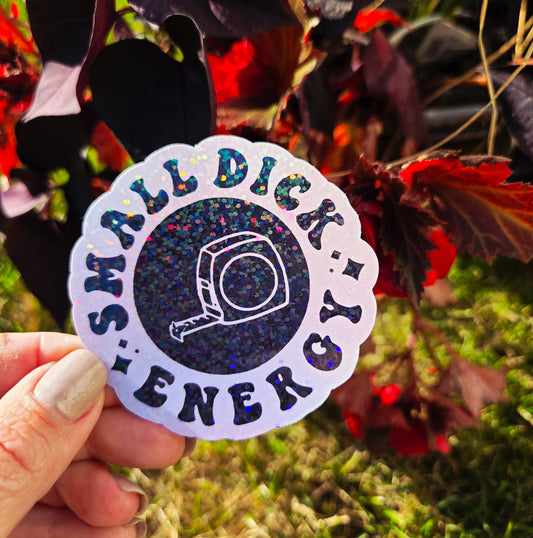Round holographic sticker with the phrase “Small Dick Energy” and an illustrated tape measure in the center