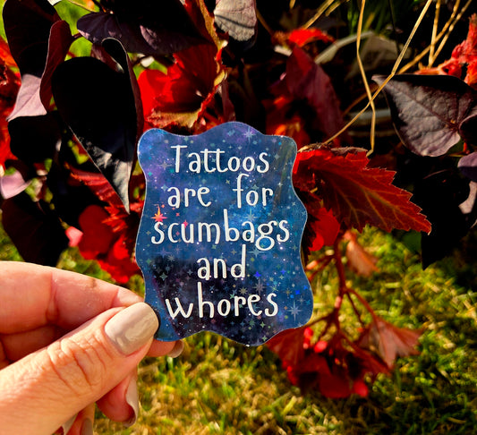 Holographic sticker with the sarcastic quote “Tattoos are for scumbags and whores” on a galaxy background